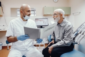 Older man siting with his dentist discussing treatment