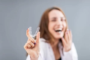 girl laughing while holding an Invisalign clear aligner