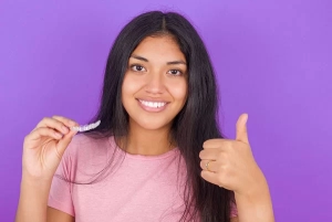young adult holding an Invisalign clear aligner