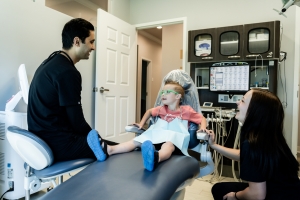 kid sitting on the dental chair and Dr. Desai talking to the child