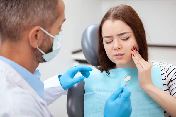 young lady showing pain discomfort while on the dental chair