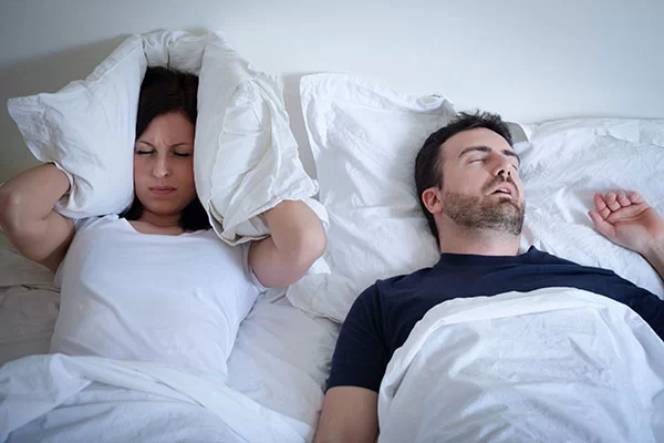 woman covering her ears to block her partner's loud snoring